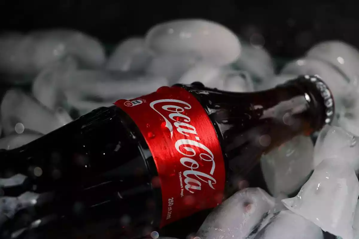 Una botella de cristal de Coca-Cola encima de hielos