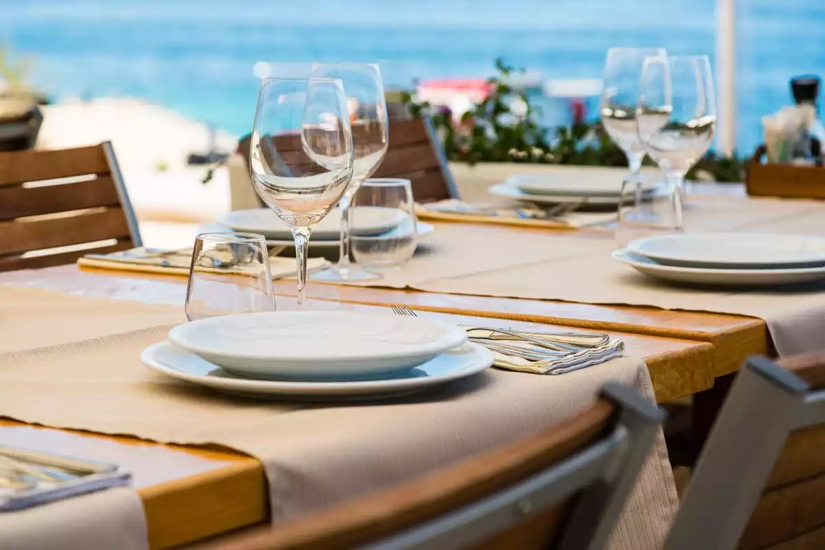 Una mesa de restaurante con cubiertos, platos y copas de vino