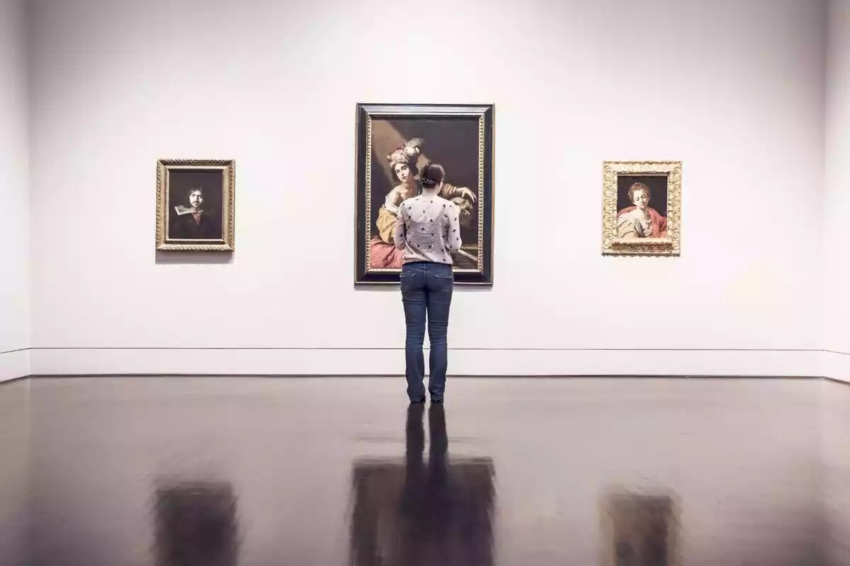 Una persona viendo tres cuadros en un museo