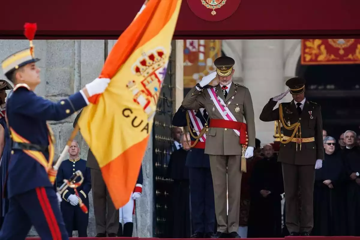 Primer plano de una bandera española en manos de un soldado desfilando ante el rey Felipe VI y militares