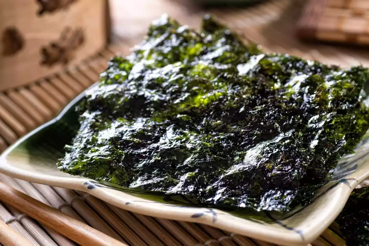Un plato de cerámica lleno de algas nori de color verde oscuro