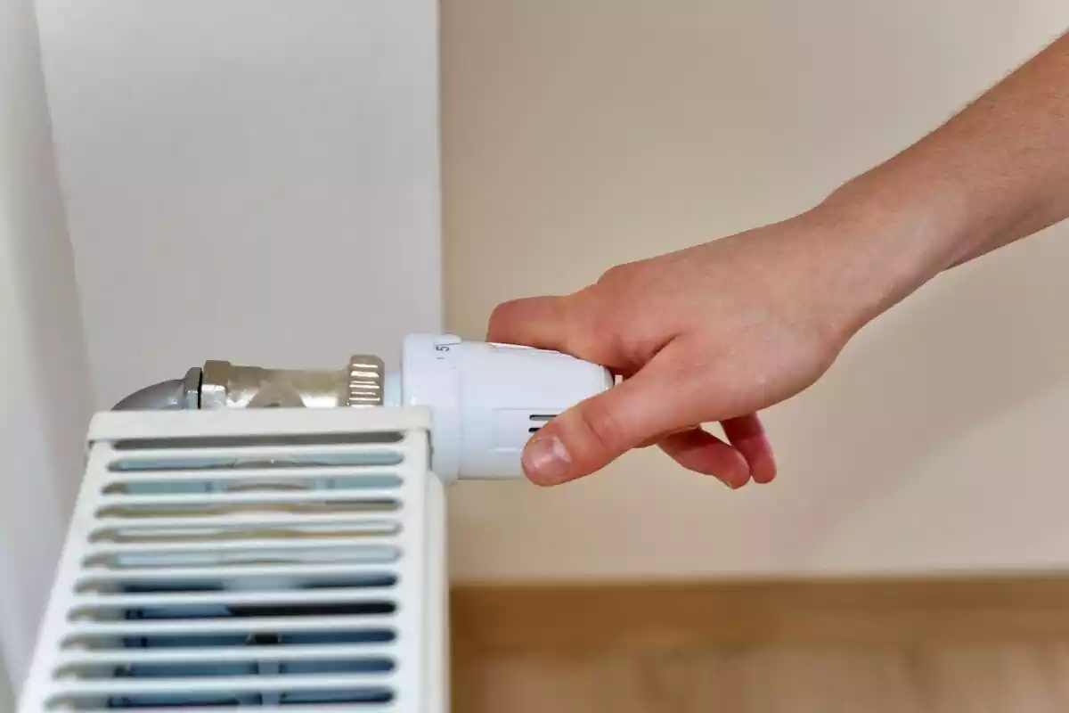Una mano modificando la temperatura de su casa con calefacción central
