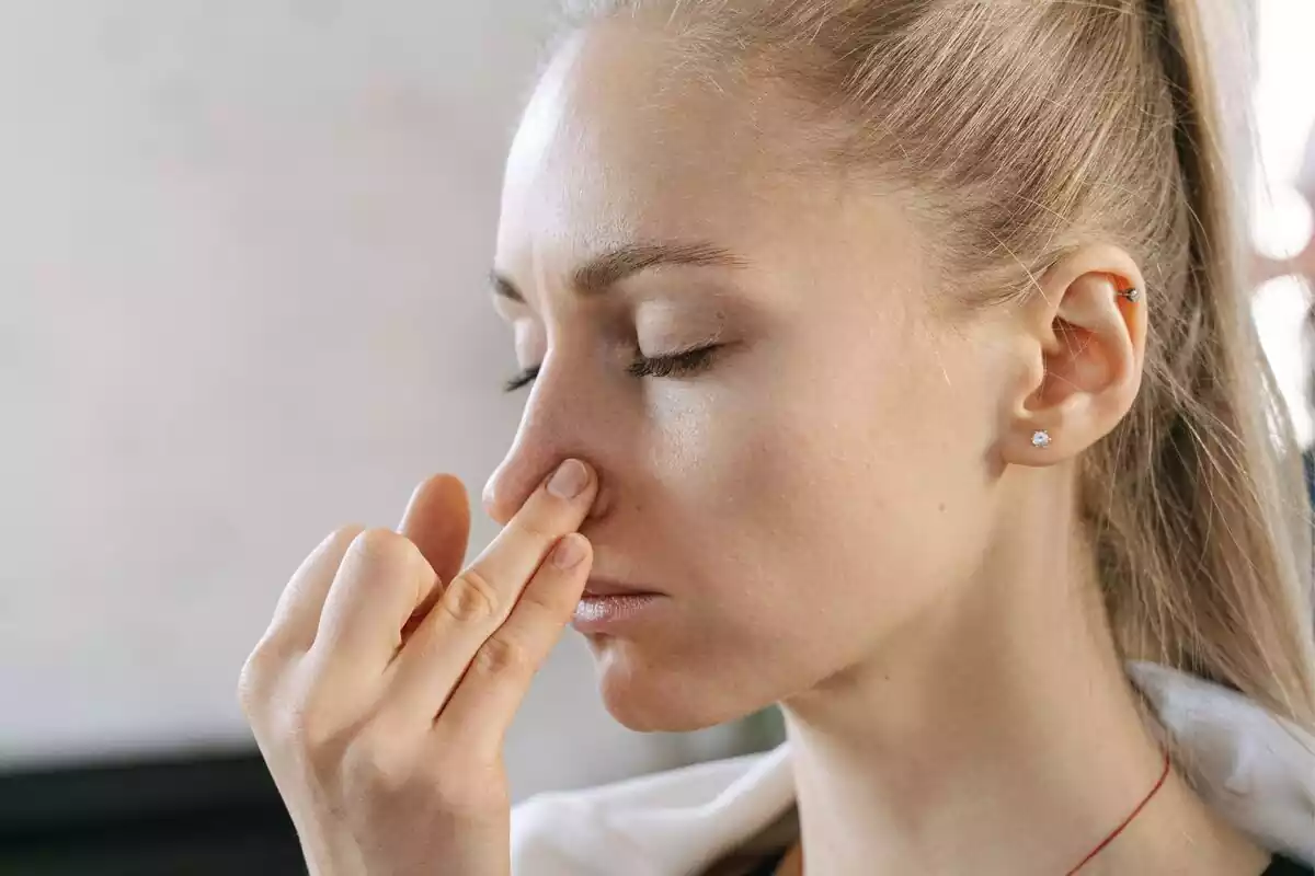 Una mujer sujetándose la nariz con los dedos mientras aguanta la respiración