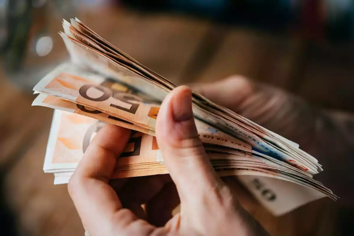 Una persona contando billetes de 50 euros con el fondo difuminado