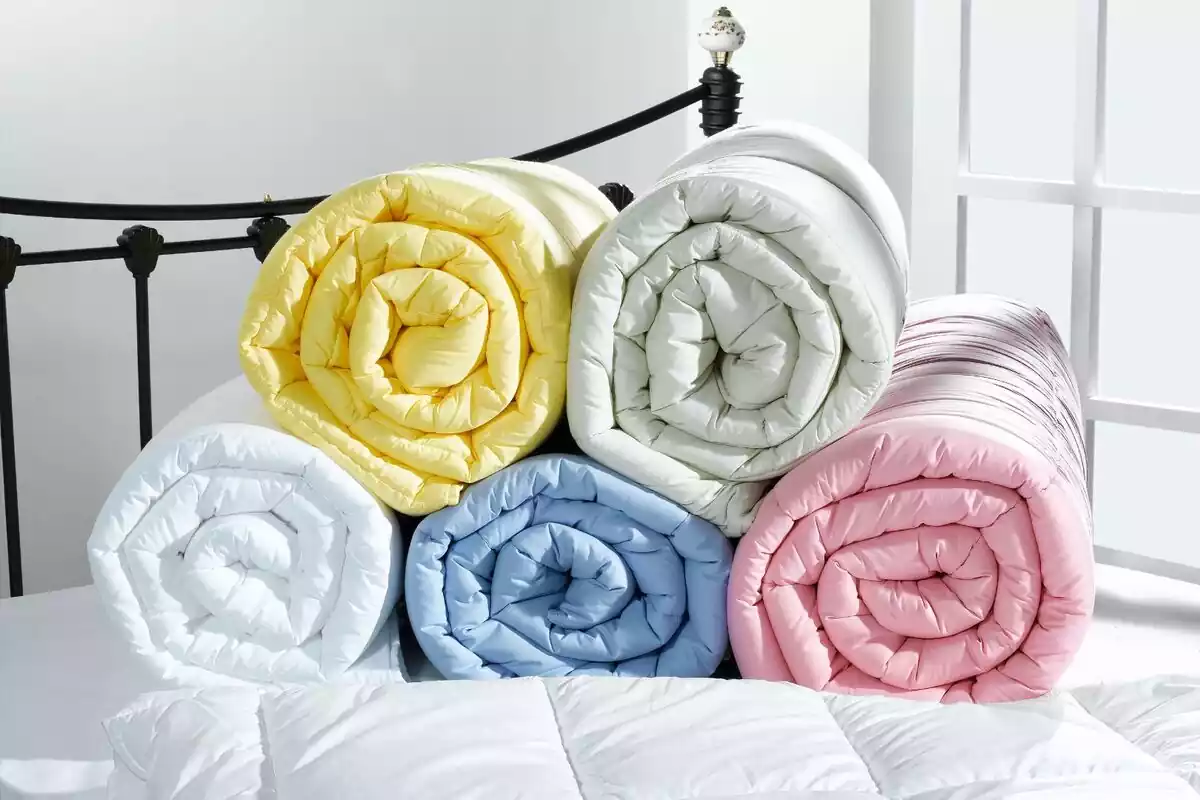 Edredones de colores apilados encima de una cama
