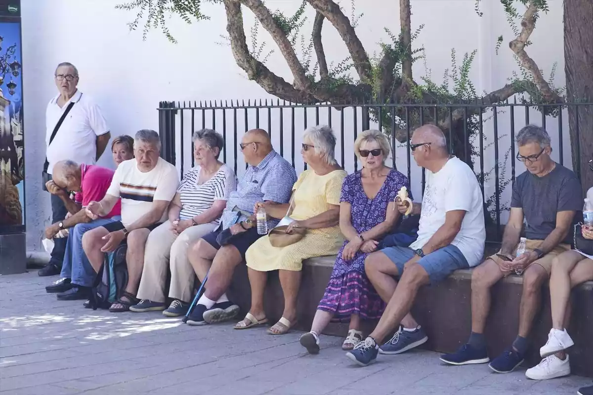 Personas mayores sentadas y comiendo en la sombra