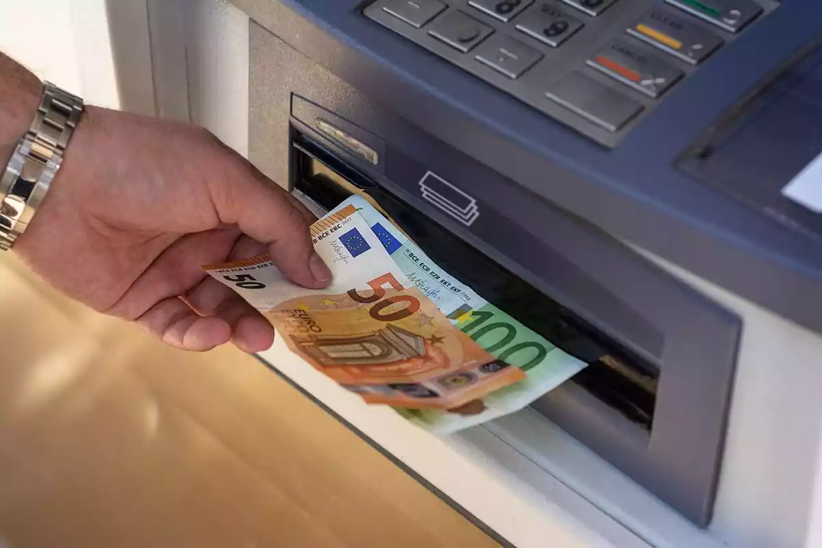 Una mano cogiendo billetes de euros de un cajero del banco