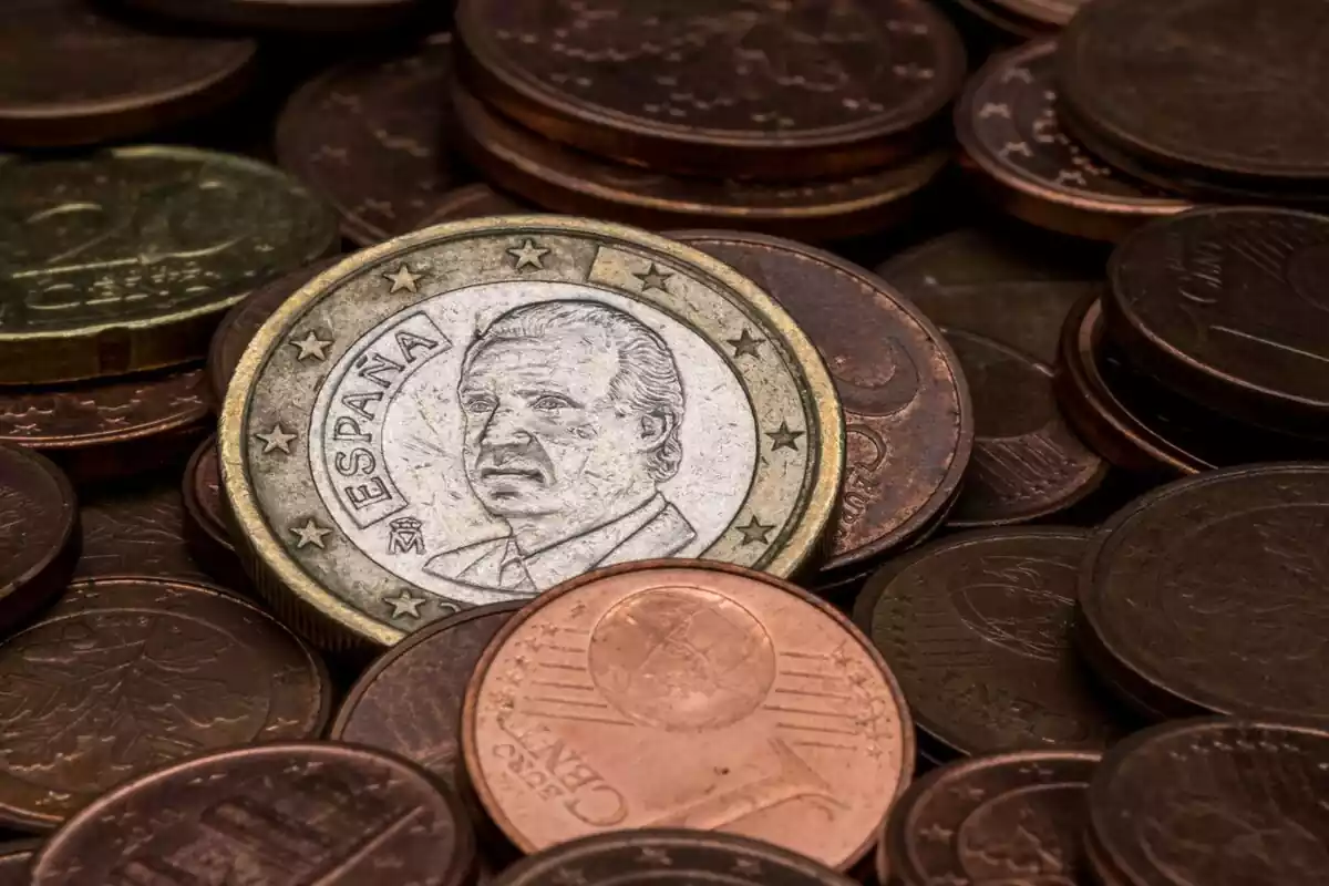 Una moneda de euro con la cara de Juan Carlos I, rey emérito, junto a muchas monedas de céntimos
