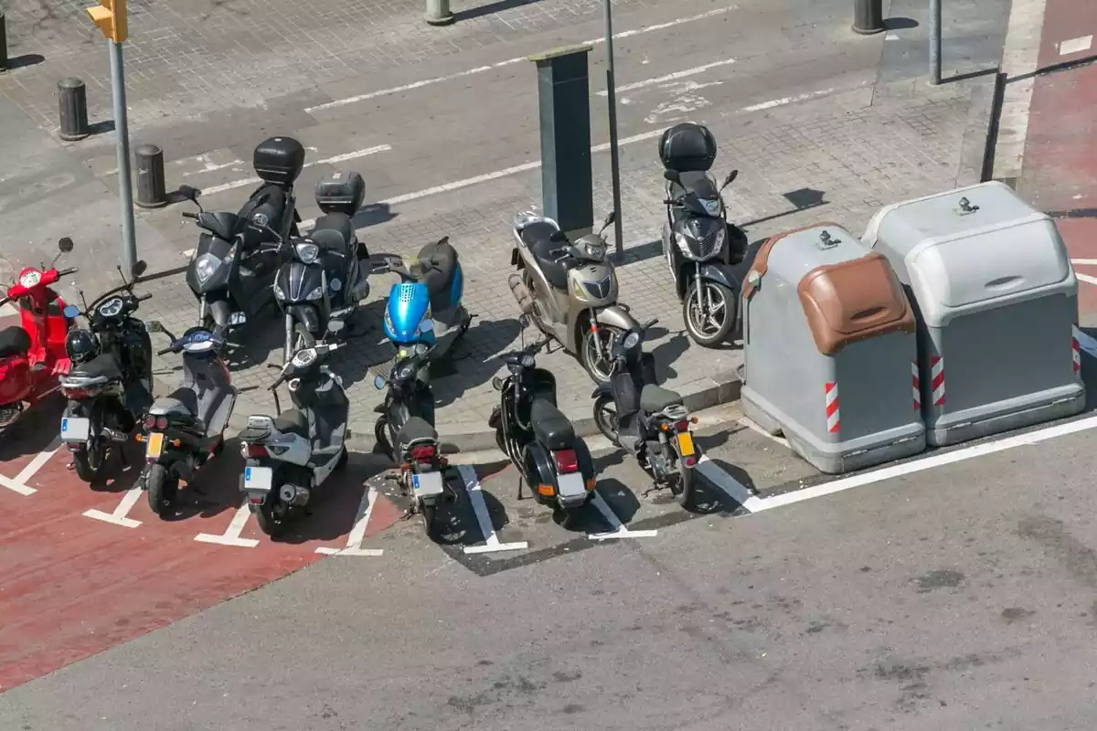 Varias motos aparcadas en la calle junto a unos contenedores