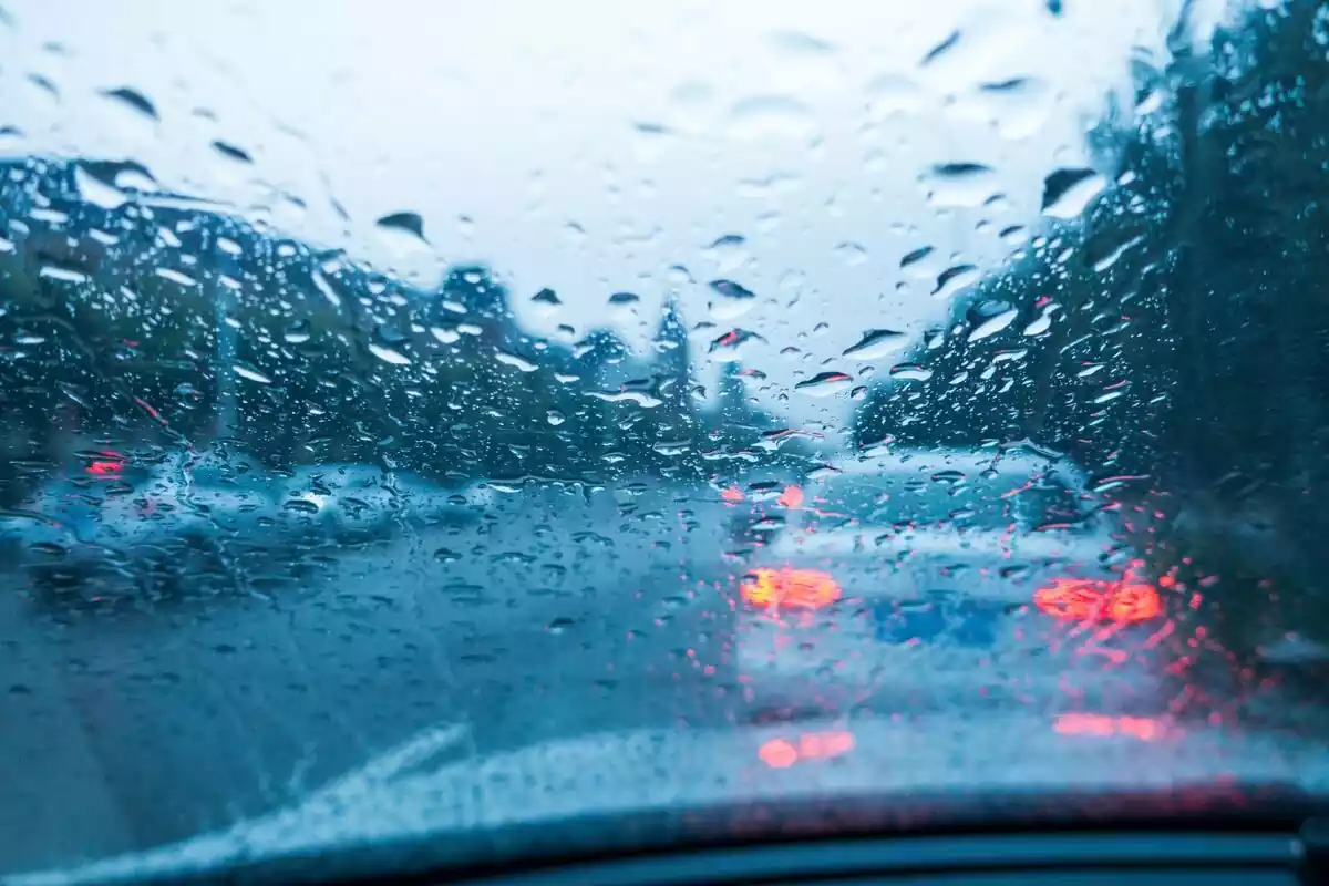 Vista frontal desde un coche en un día lluvioso con un coche blanco delante