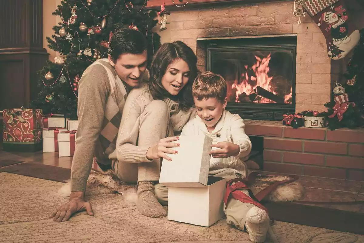 Familia celebrando la navidad en su casa abriendo los regalos delante de la chimenea