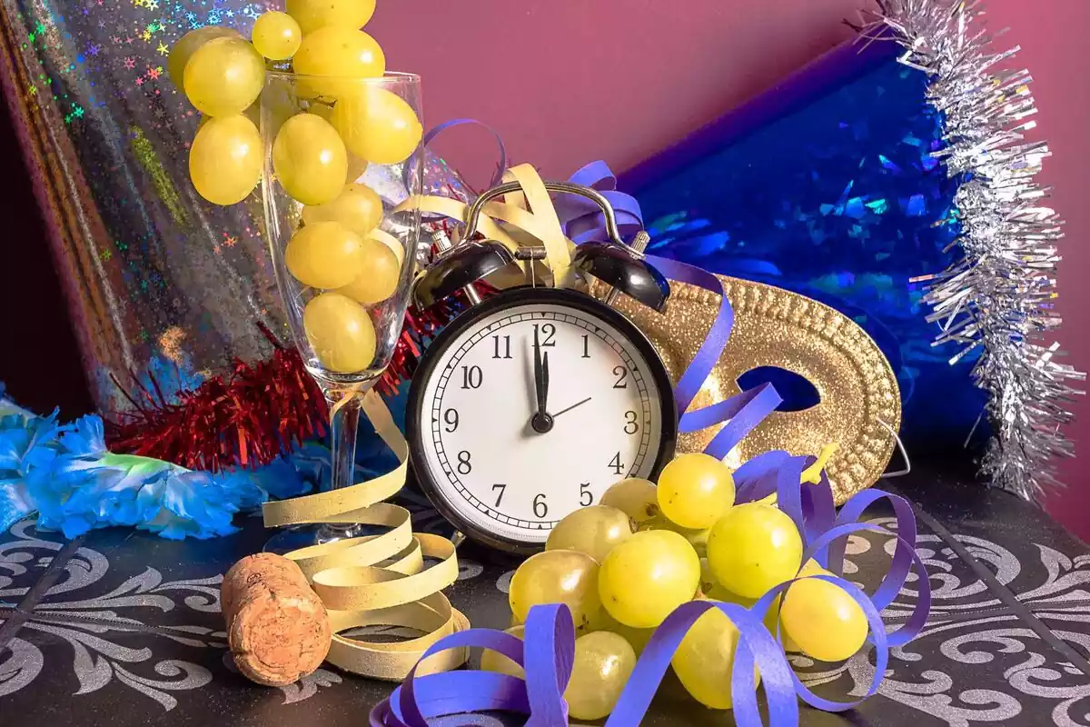Imagen de fin de año, con un reloj, unas uvas y cotillón.