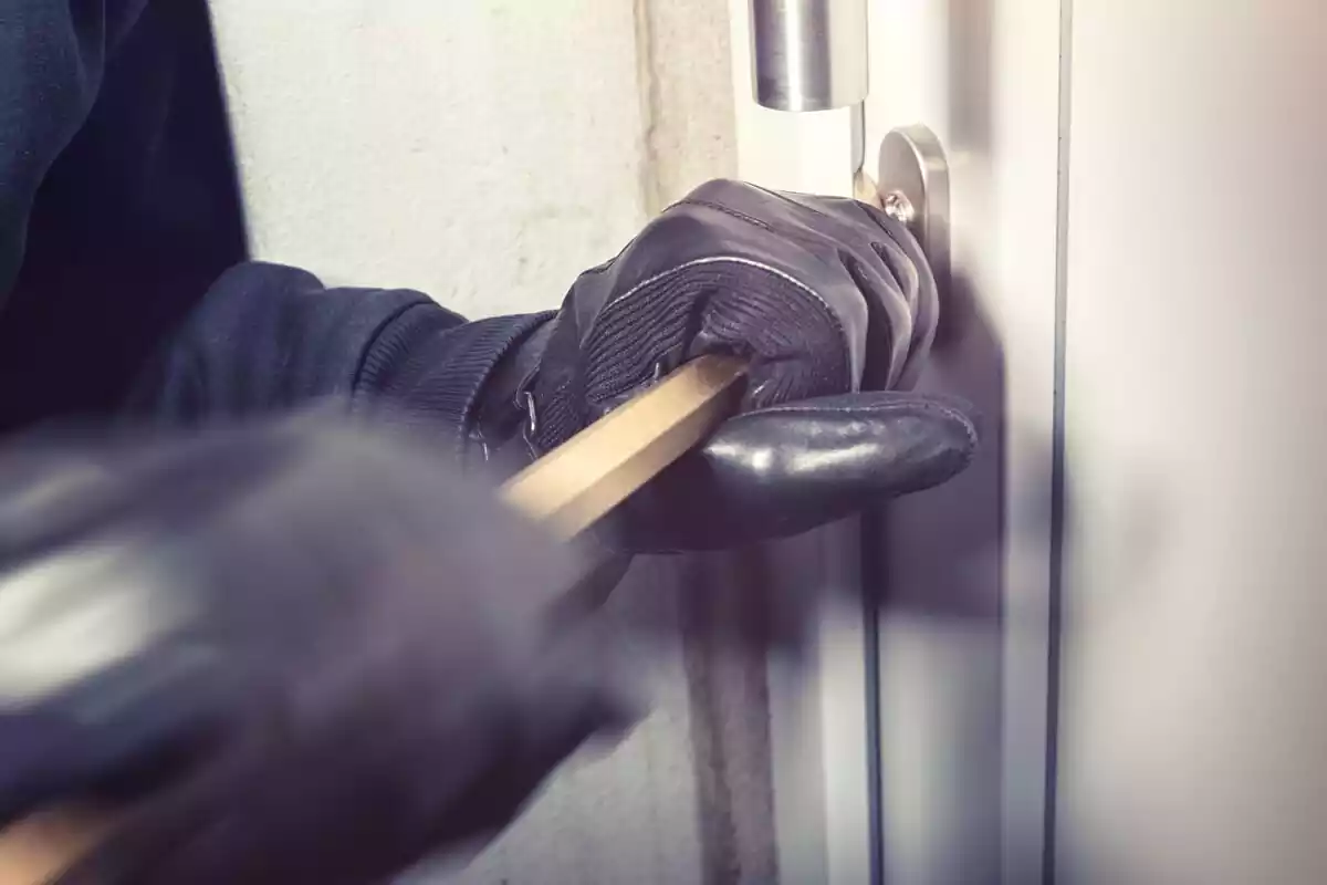 Imágen de un ladrón forzando la puerta de una vivienda con una palanca