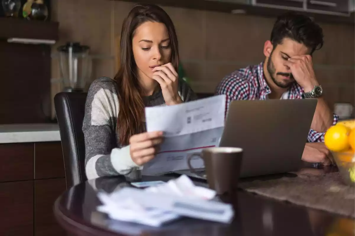 Imágen de una pareja mirando unas facturas en su casa