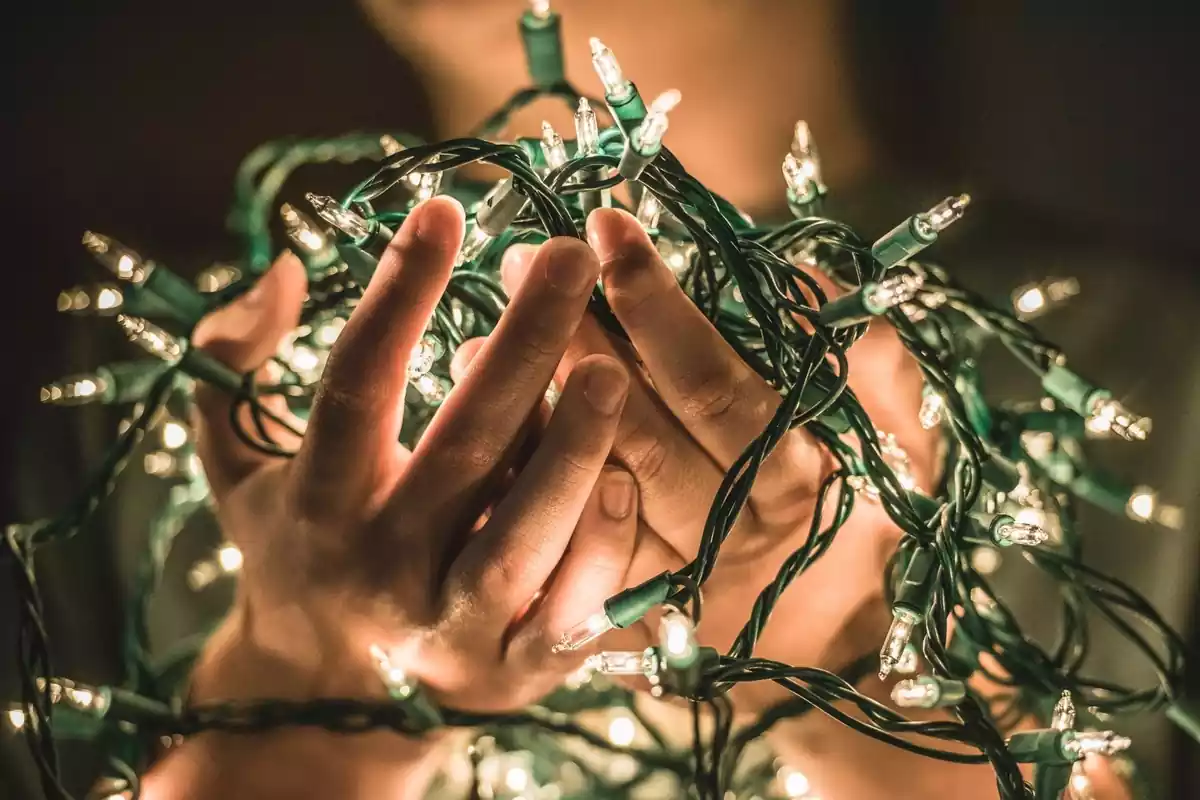 Imagen de unas manos sujetando unas luces de navidad