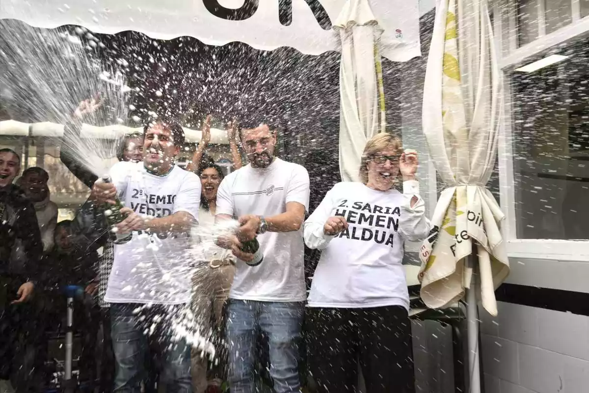 Tres personas con camisetas blancas celebrando los premios de Lotería