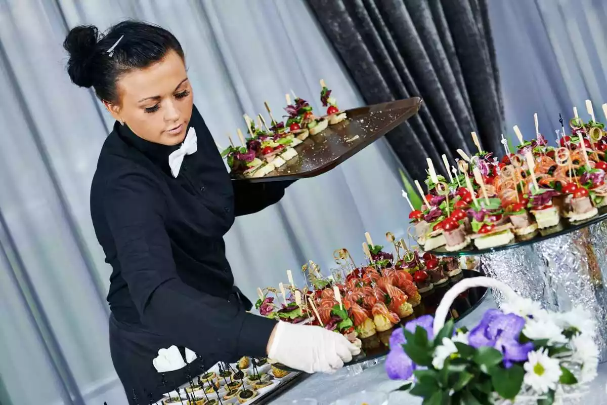 Una camarera colocando comida sobre una mesa