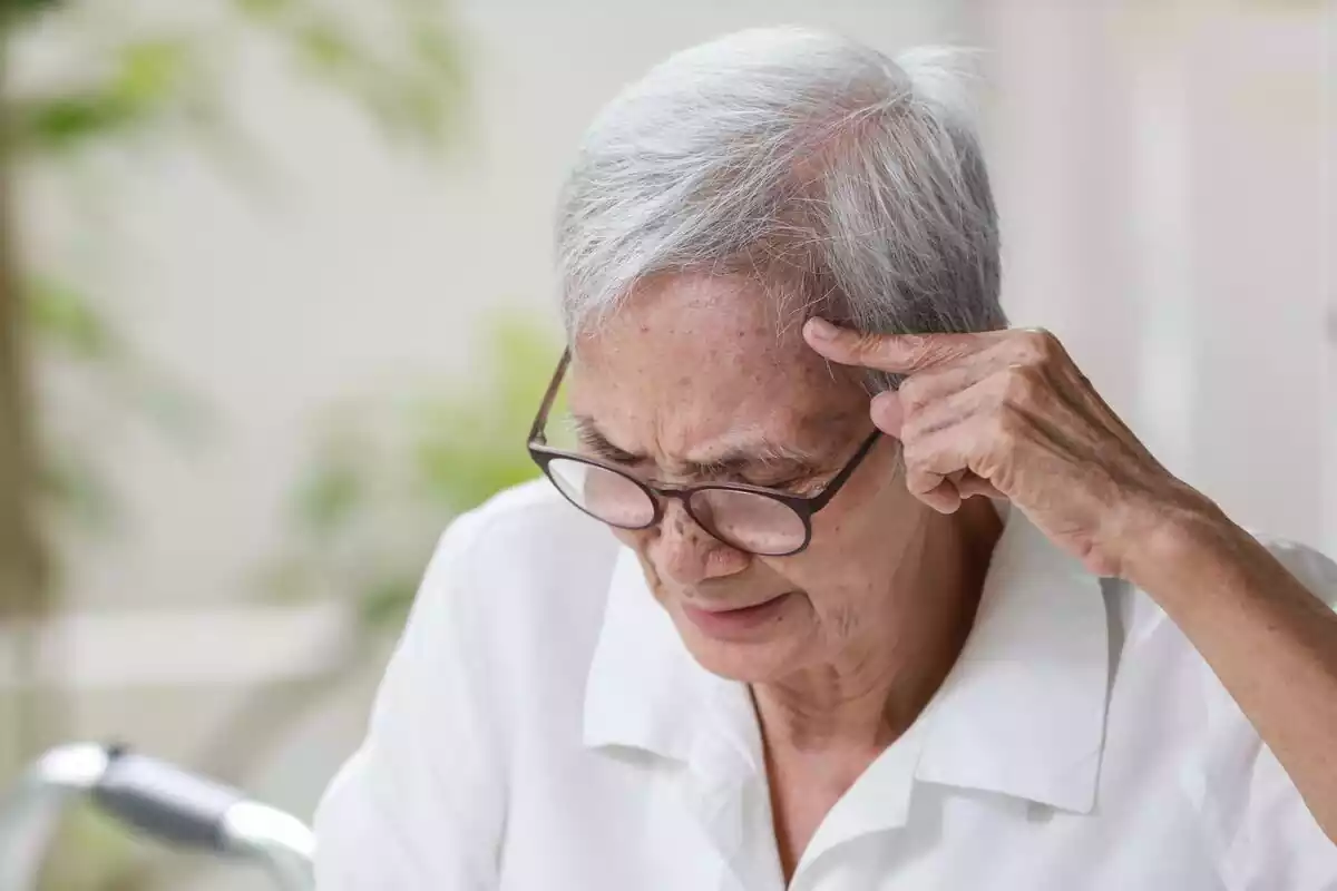 Una mujer mayor tocándose la cabeza con un dedo