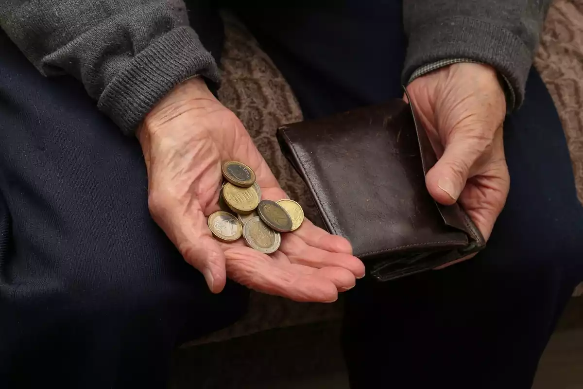 Imagen de una persona mayor sujetando monedas de euro con las manos