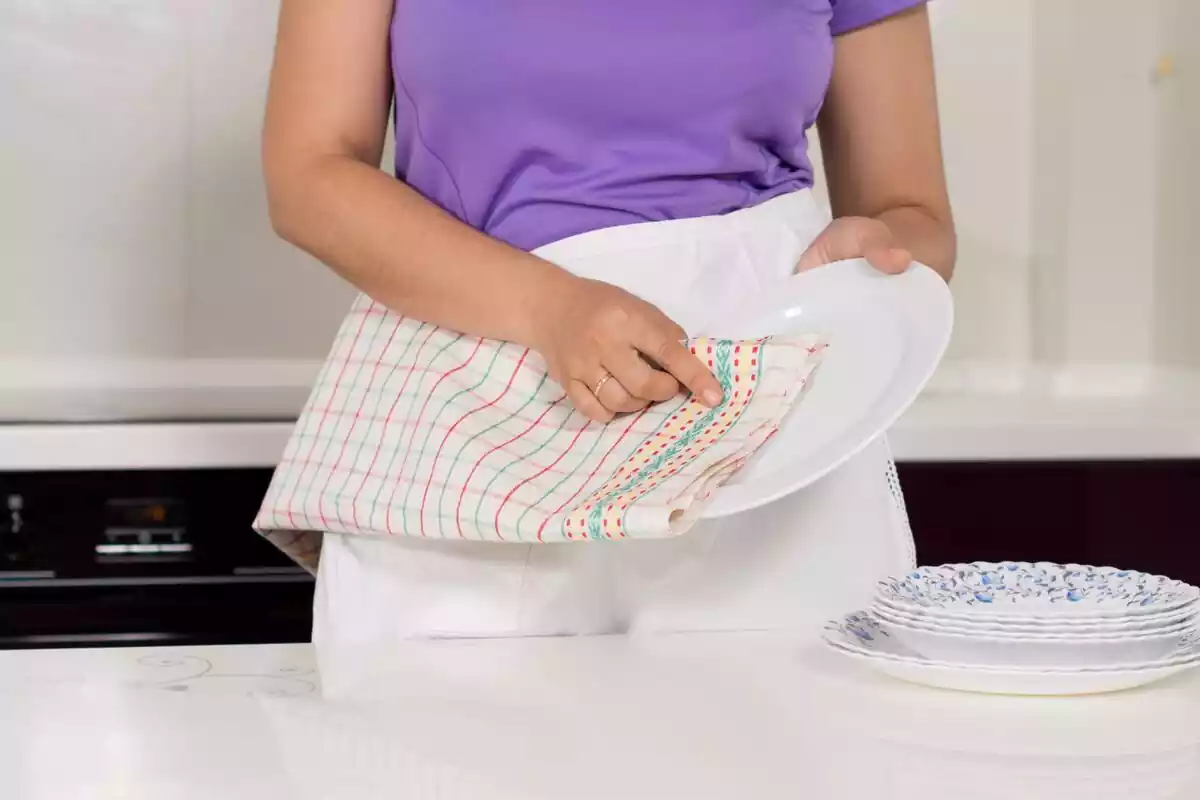 Mujer secando un plato con un paño de cocina