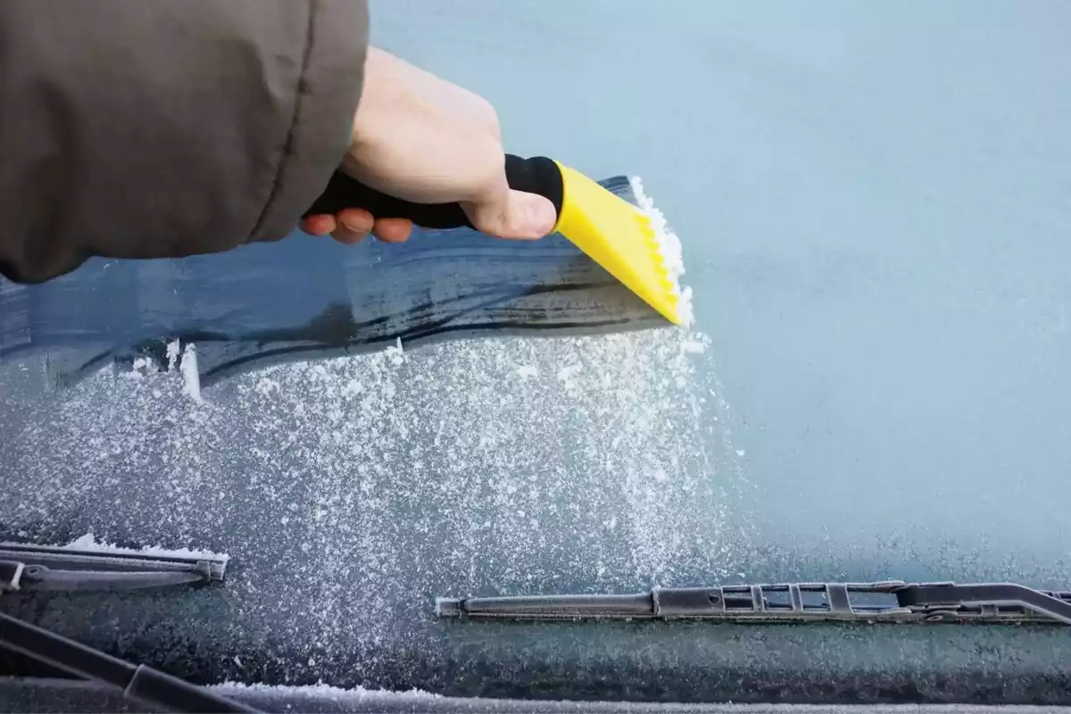 Una persona quitando el hielo del parabrisas de su coche