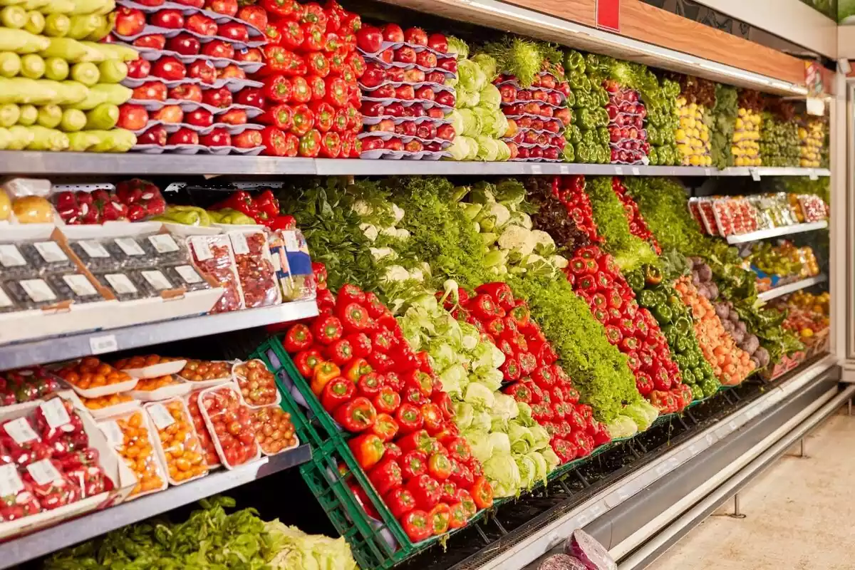 Estantes repletos de verduras en un supermercado