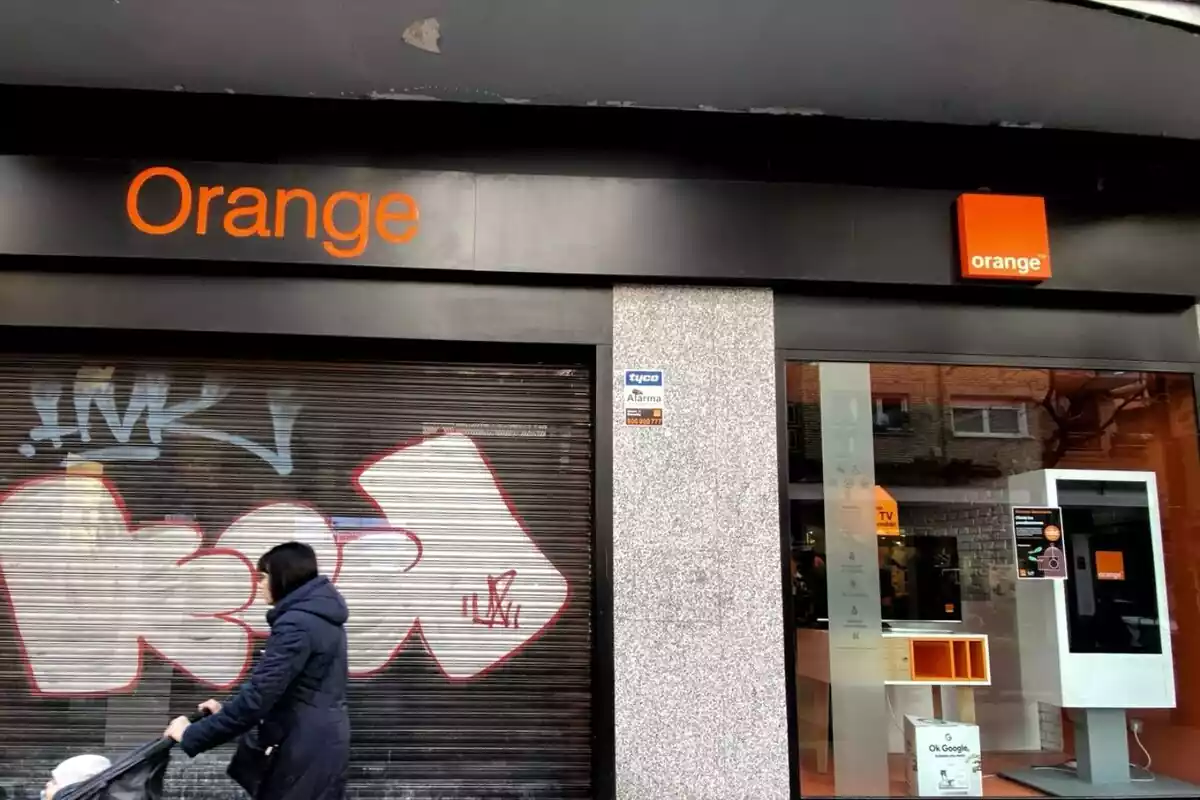 Exterior de una tienda Orange con una mujer pasando por delante
