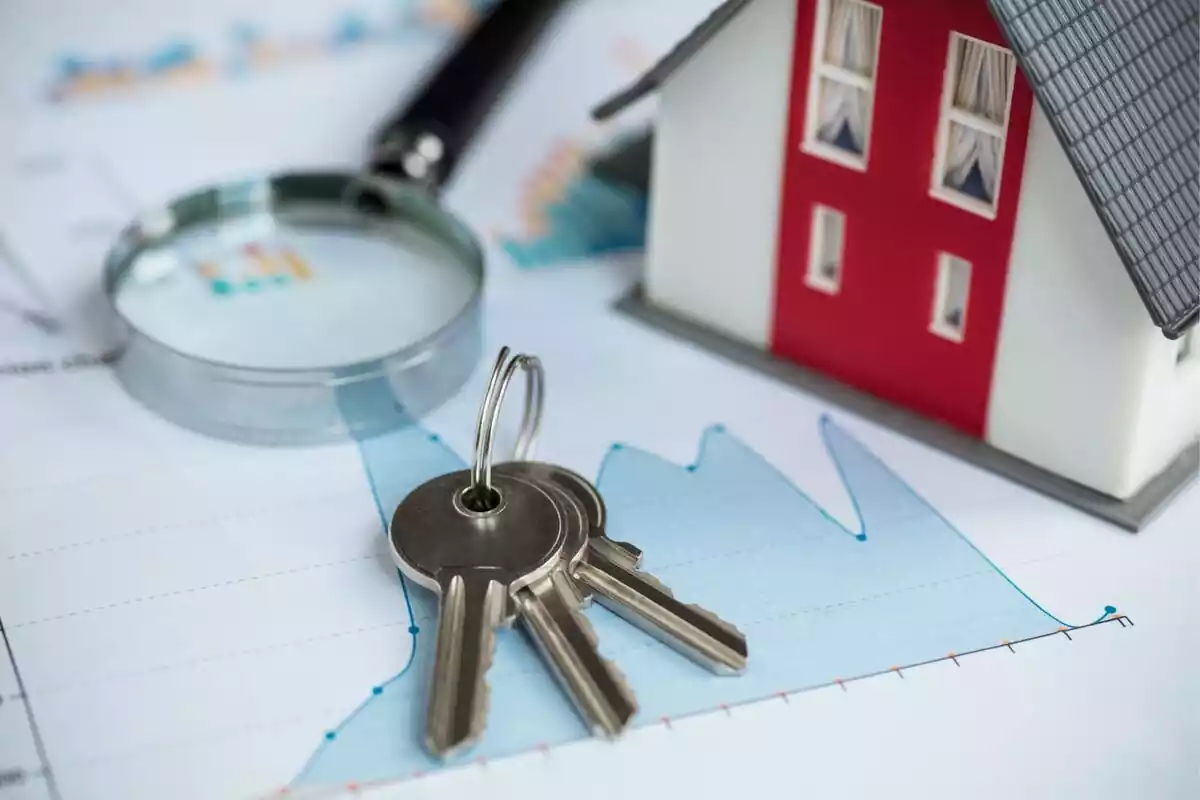 Unas llaves y una casa de fondo simulando una hipoteca