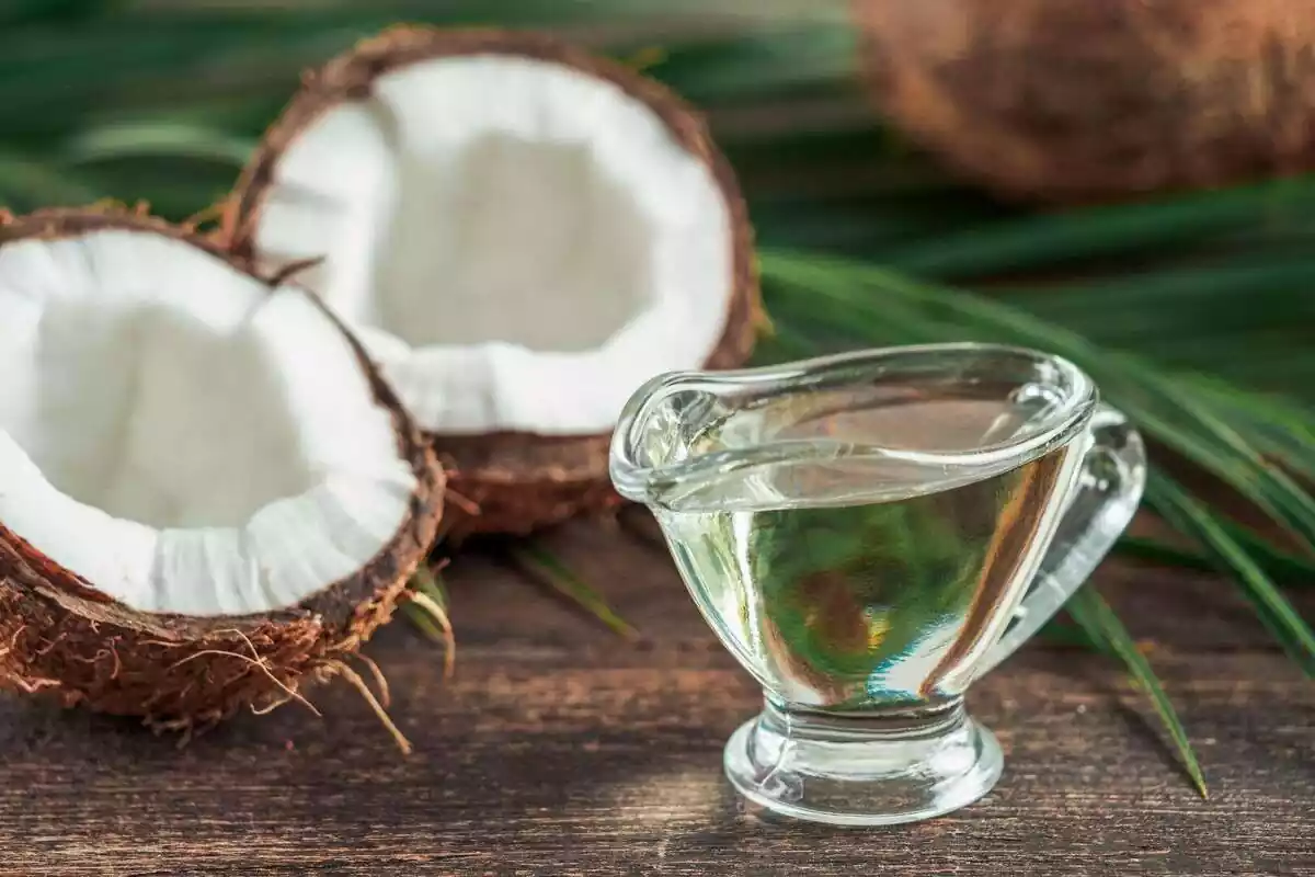 Close-up of a glass bowl with coconut oil in the background is half a coconut.