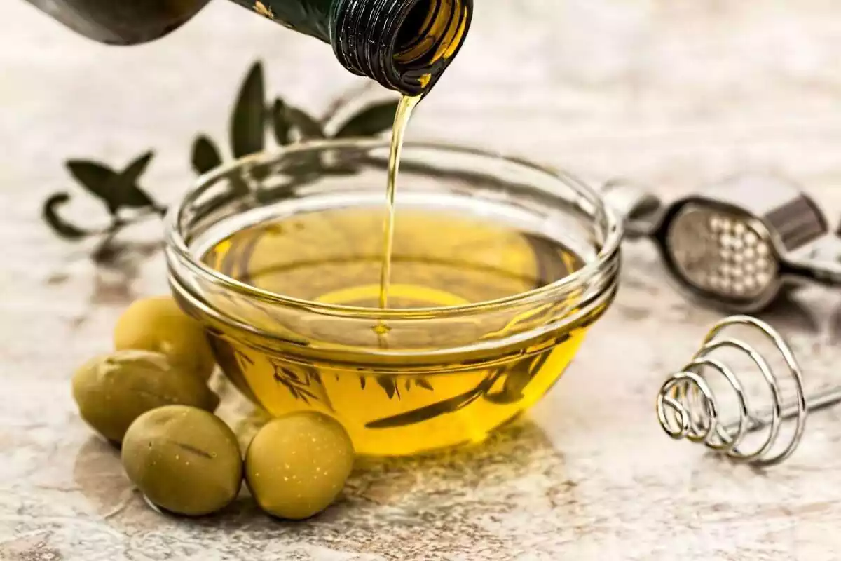 Close-up of an olive oil bottle next to some olives.