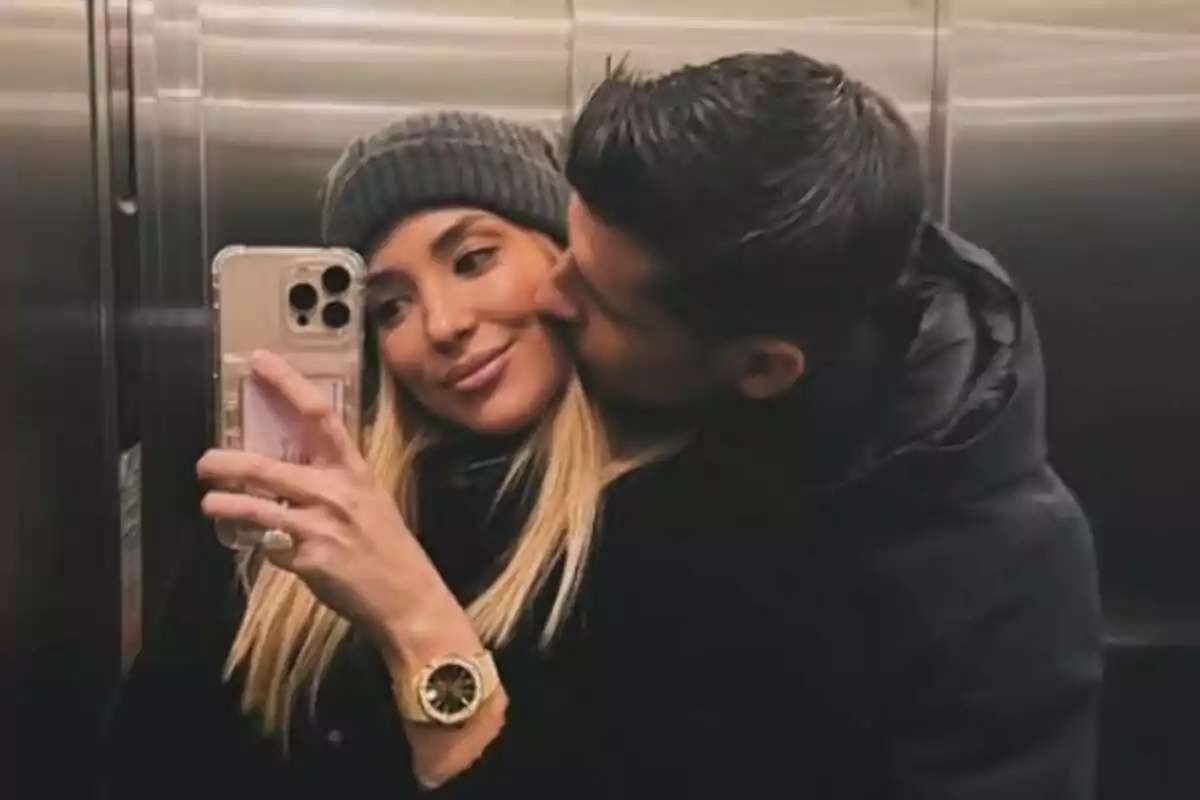 Imagen de Alice Campello y Álvaro Morata tomándose una selfie en un ascensor, donde ella sostiene el teléfono y él le da un beso en la mejilla. Imagen de Alice Campello y Álvaro Morata tomándose una selfie en un ascensor, donde ella sostiene el teléfono y él le da un beso en la mejilla.