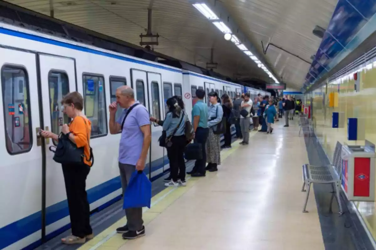 Varios pasajeros en el andén del Metro de Madrid a punto de entrar en un tren