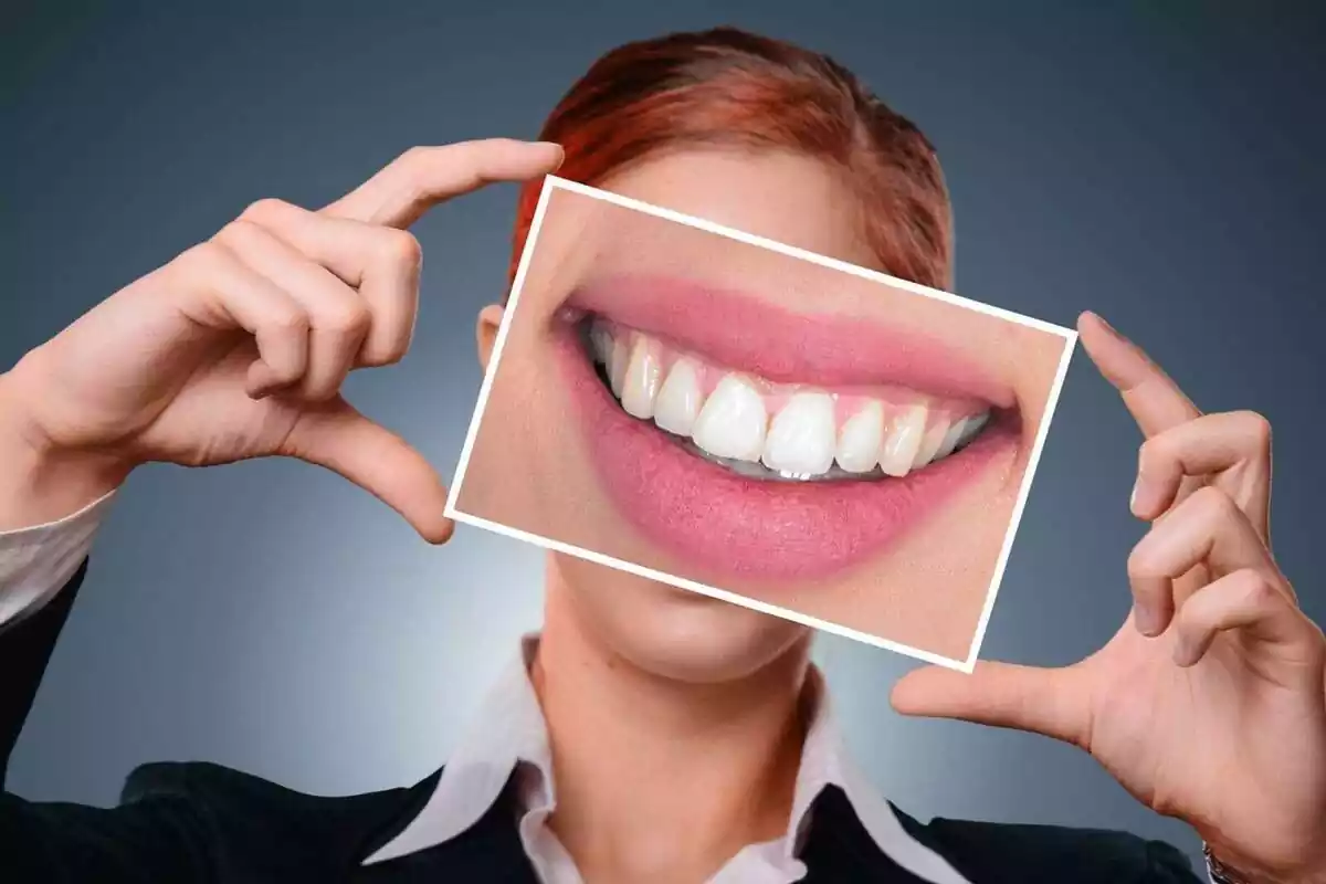 Una mujer sujetando una imagen de una boca sonriente