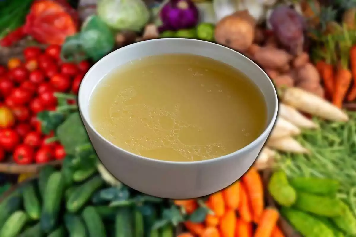 A bowl of broth with a group of vegetables in the background