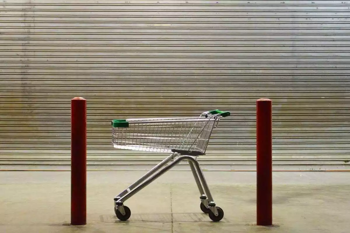 Primer plano de un carrito de la compra delante de un supermercado cerrado