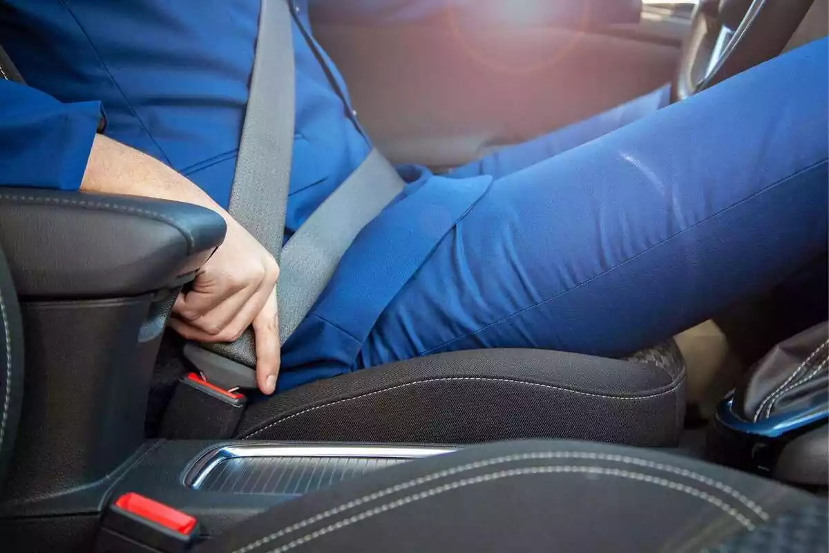 Primer plano de una persona poniéndose el cinturón de seguridad en un coche