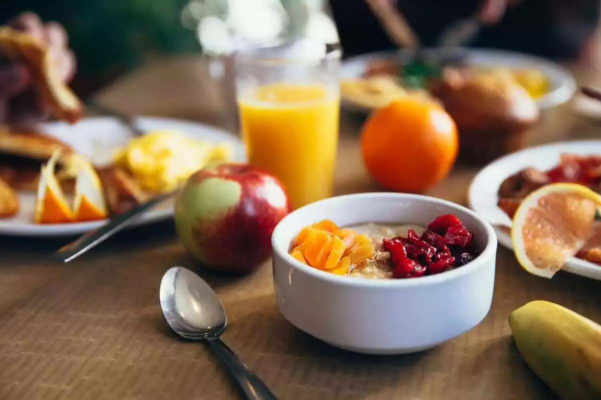 Varios platos de comida para desayunar con algunas frutas y un zumo de naranja