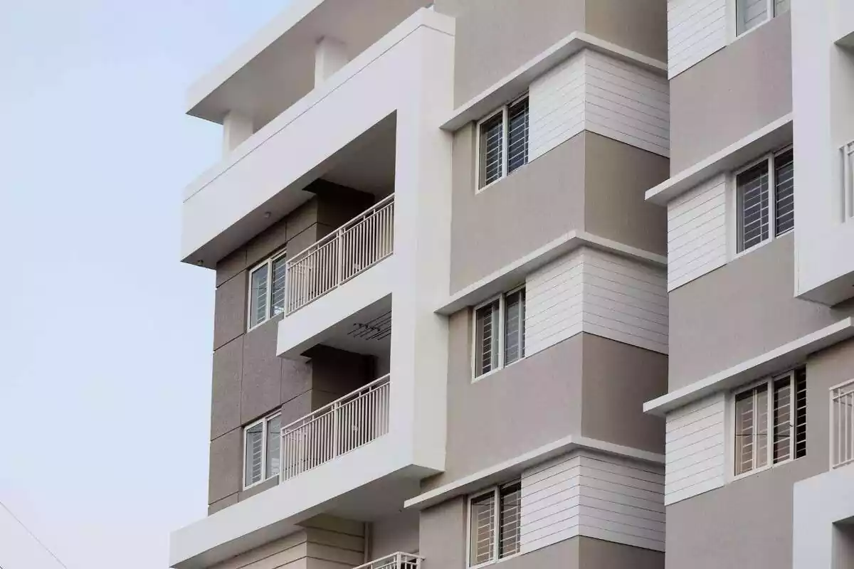 Exterior de un edificio de color gris y blanco con balcones y ventanas