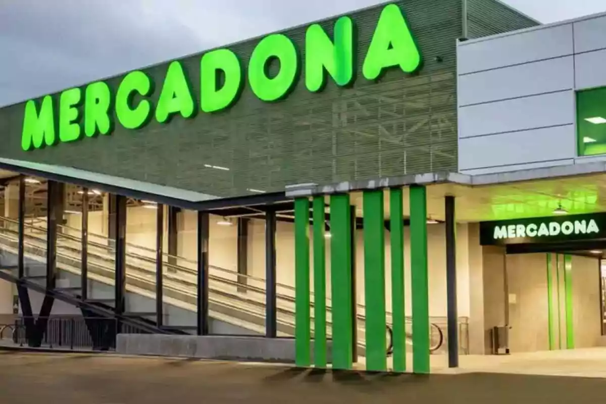Fachada de un supermercado con letrero verde iluminado.