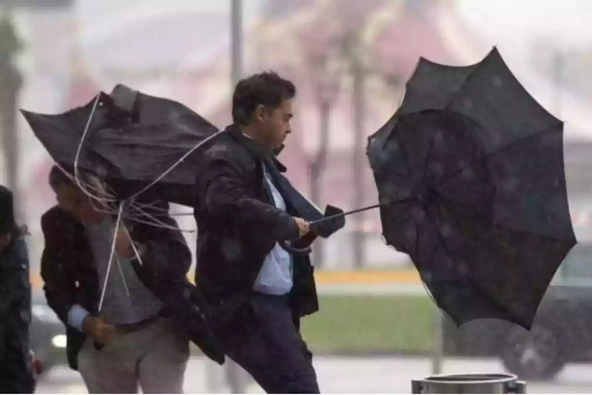 Hombre con el paraguas del revés por el temporal de lluvia y viento