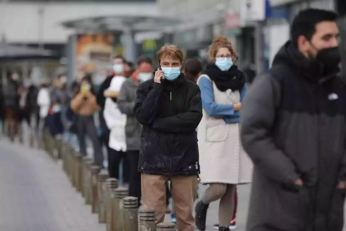 Un grupo de personas con mascarillas haciendo cola para ser vacunados durante la pandemia