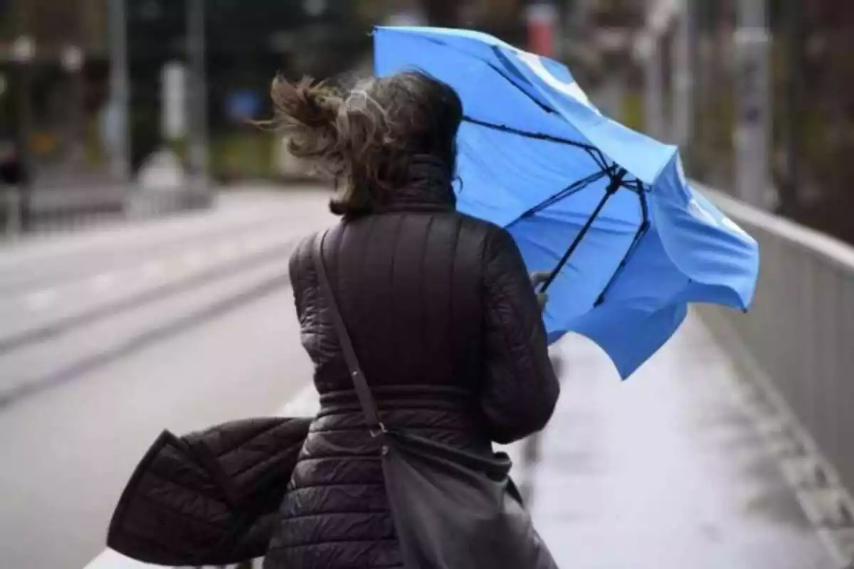 Mujer sujetando un paraguas en medio de un temporal de lluvia y viento
