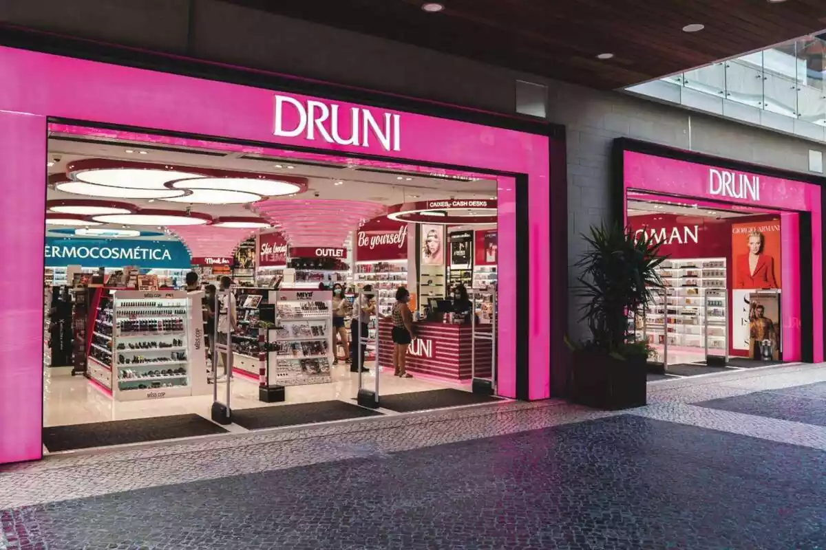 Exterior de una tienda de Druni con el logo en una pared de color rosa y gente comprando