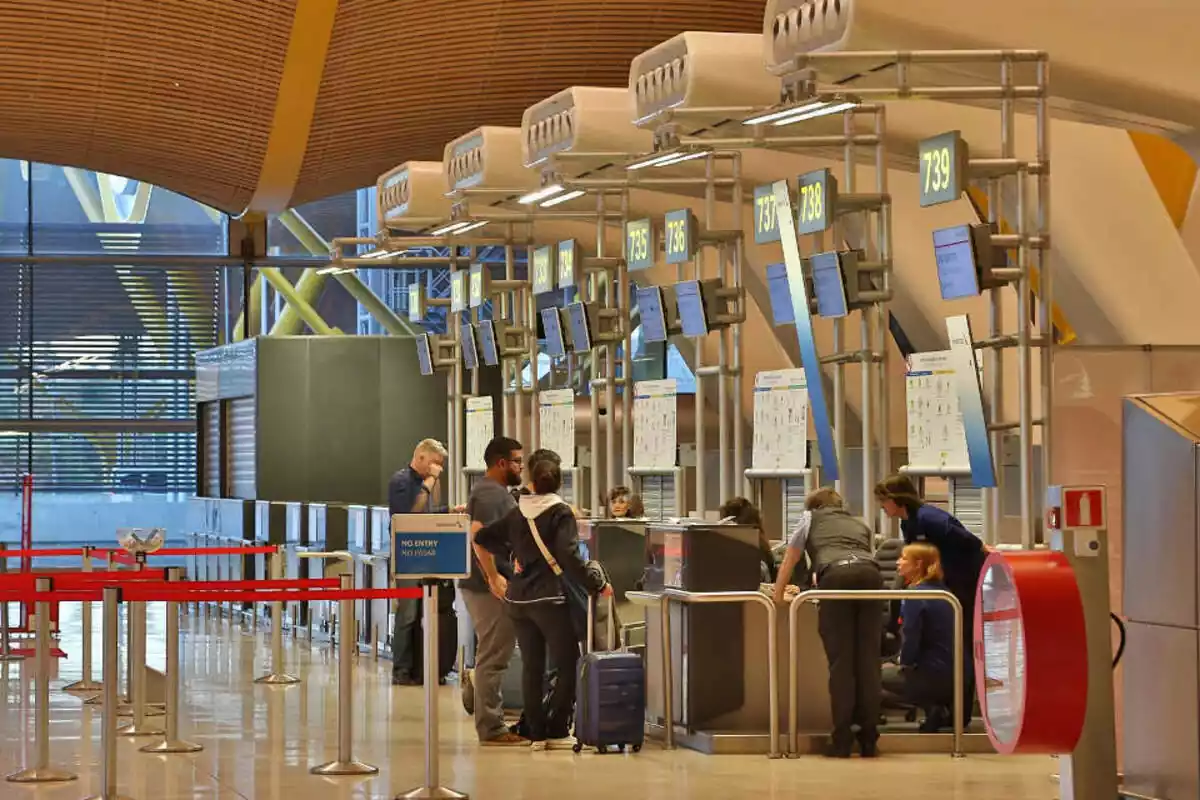 Interior de un aeropuerto con varias personas con maletas