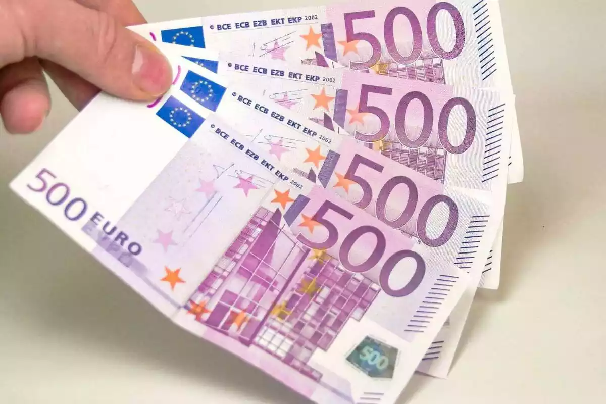 Mano sujetando cuatro billetes de 500 euros