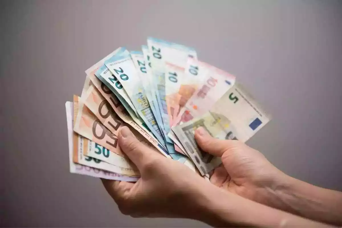 Dos manos sujetando billetes de euro