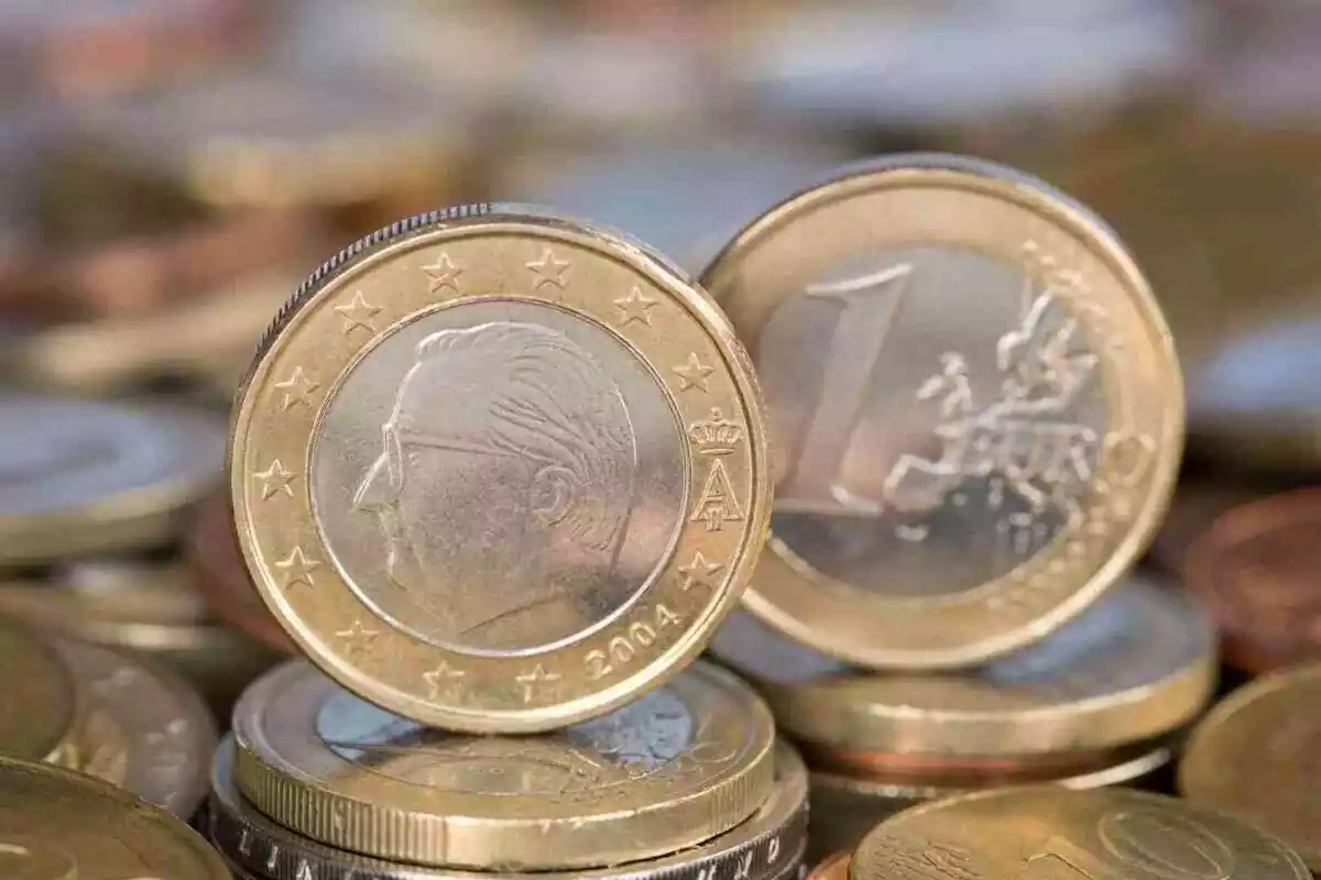 Dos monedas de euro en postura vertical encima de muchas otras monedas de euro en postura plana