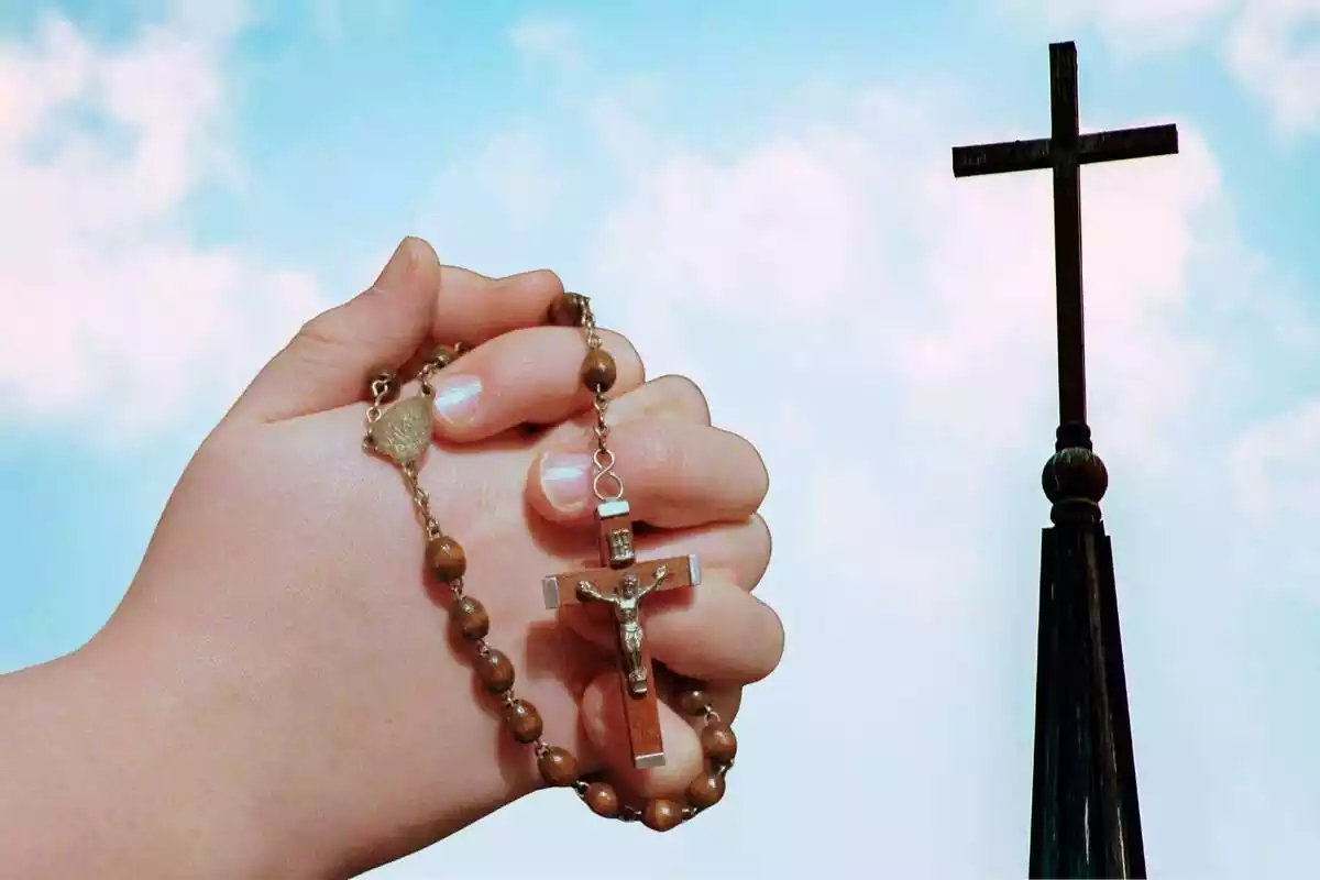 Montaje de una cruz y las manos de una persona rezando
