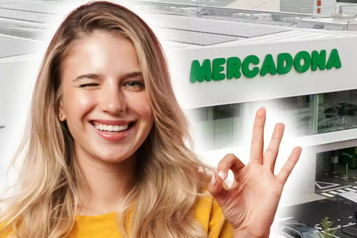 A smiling person winking and making the "ok" hand gesture in front of a building with the logo of a supermarket that is Mercadona.