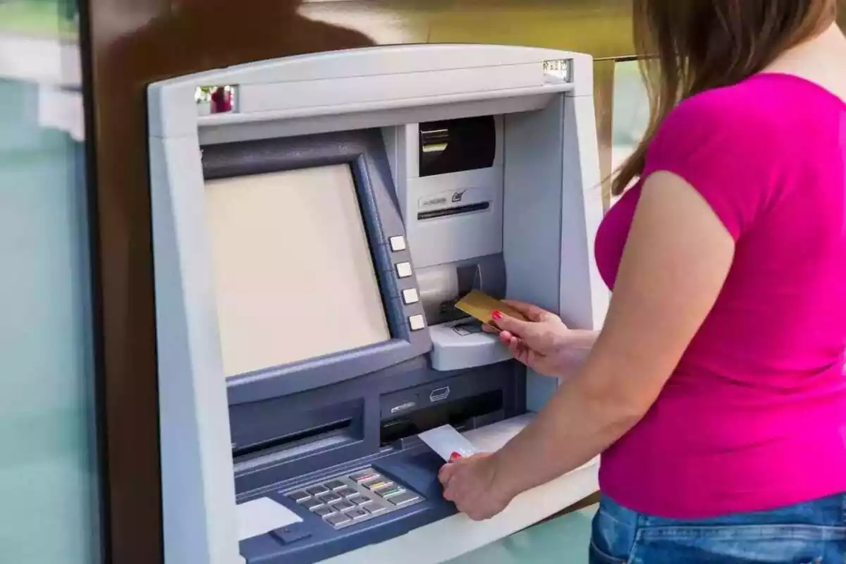 Mujer introduciendo una tarjeta de crédito en un cajero automático